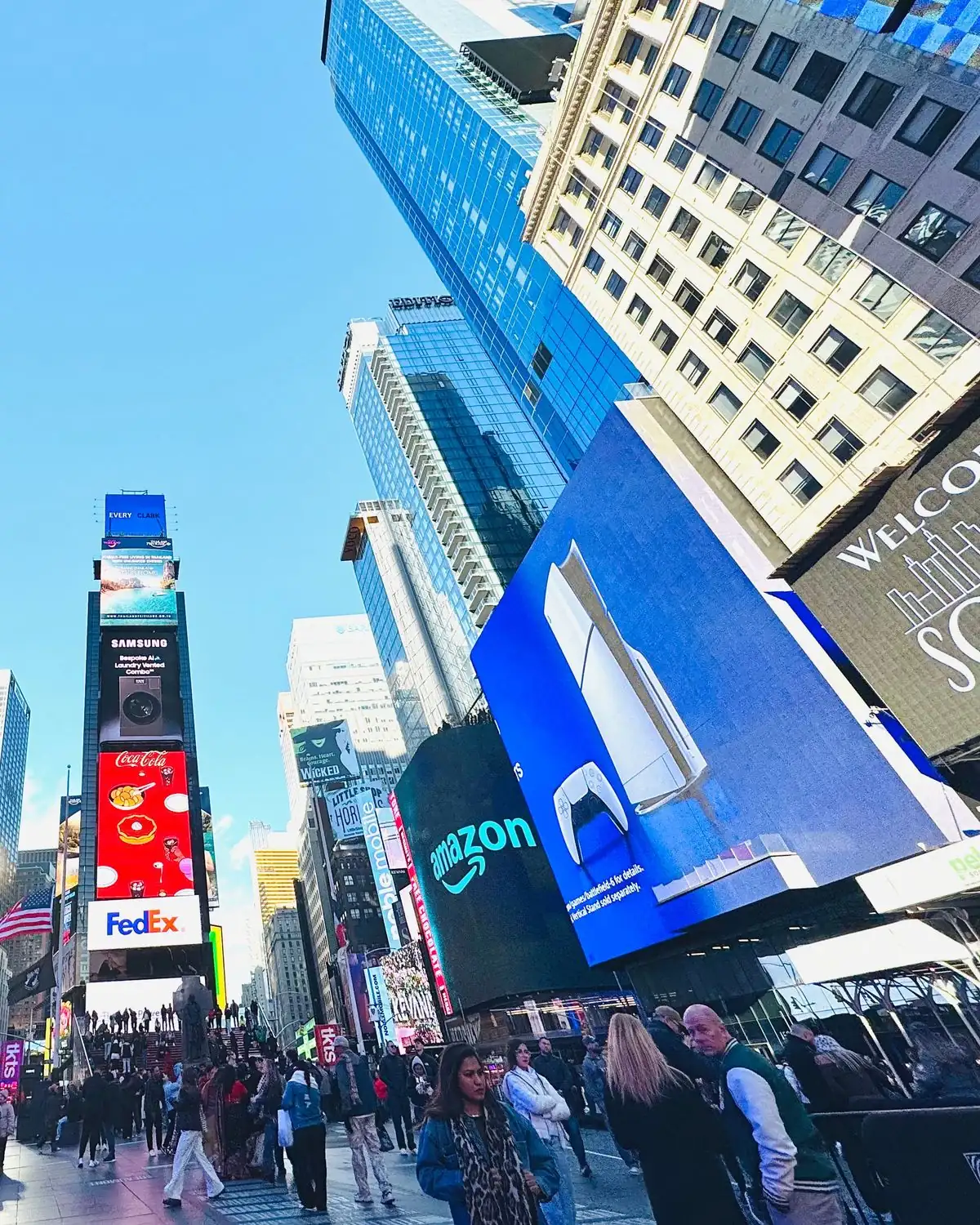 Digital billboards over a crowded city street at dusk.